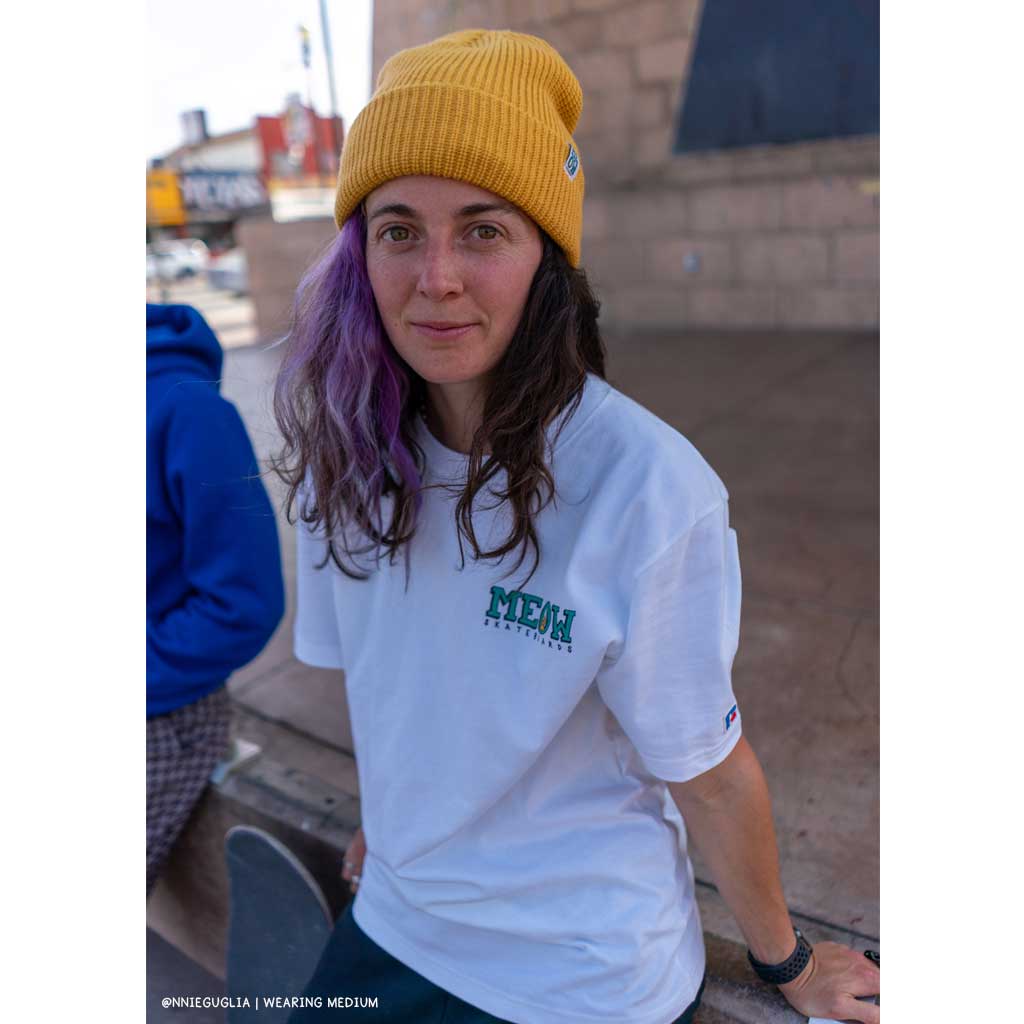 Annie Guglia wearing white bar logo tshirt and yellow beanie sitting on stage